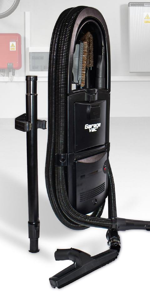 The GarageVac GH120 in black: the wall-mounted unit with its 35-foot hose coiled around it, cleaning tools stored in the top caddy, telescoping wand and bare-floor tool alongside.